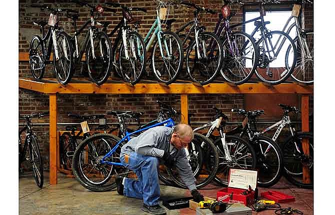 Chuck Hager, father-in-law of Red Wheel Bike Shop owner Nick Smith, looks for a new bit while helping install shelves Saturday on the brick walls of the Jefferson City store's new Millbottom location at 400 W. Main St. 
