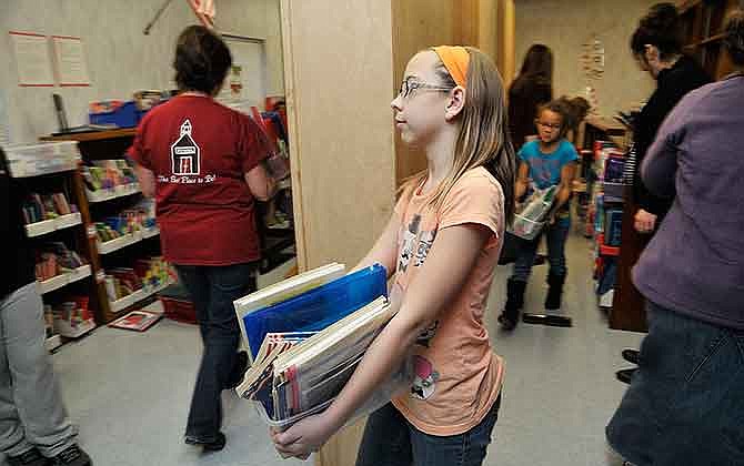 Several members of East School's PTO and students were at the Jefferson City school Thursday to help get the kindergarten classroom ready. The Reading Recovery Program was moved out of the trailer to make room for a fifth-grade class and kindergarten class. Aubrey Gogel, a fifth-grade student, helps carry materials from one side of the room to the other to be placed on shelves.