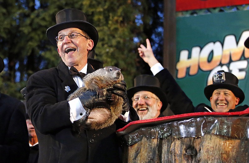 Groundhog Club handler Ron Ploucha, left, holds Punxsutawney Phil, the weather prognosticating groundhog, during Monay's 129th celebration of Groundhog Day on Gobbler's Knob in Punxsutawney, Pa. Even with snow falling, Phil "saw" his shadow, predicting six more weeks of winter weather.