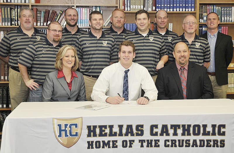 Hale Hentges (seated center) of Helias High School signs a letter of intent to play football at the University of Alabama during a ceremony Wednesday morning in the school library. Also seated are his parents, Jennifer and Chris Hentges. Standing (from left) are Helias assistant coaches Ron Eickmeyer, Adam McMorris, Andy Pitts, Brent Mettlen, Jason Becker, Jeff Pickering, Brad Hake, Mark Ordway and Ben Balk.