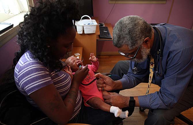 Dr. Wendell Wheeler gives vaccinations to Ny-riel Wilson, as her mother Briana Steele, holds her on Tuesday, Feb. 3, 2015 in South Holland, Ill. Ny-riel Wilson was not vaccinated for measles during this visit because she is too young for that vaccination.