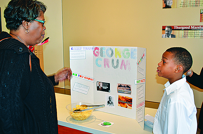 Derese Heredon, left, samples a potato chip while listening to John James, 8, tell her about George Crum, the inventor of potato chips. James and about 11 other youth showed off their displays at Quinn Chapel AME's second annual Black History Museum, in conjunction with Black History Month.