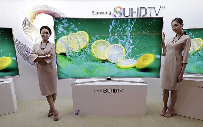 In this Jan. 5, 2015 photo, models pose with a Samsung Electronics Co.' SUHD 4K smart TV during a press conference in Seoul, South Korea. Samsung Electronics Co. on Tuesday, Feb, 10, 2015, said voice recognition technology in its Internet connected TVs can capture and transmit nearby conversations.