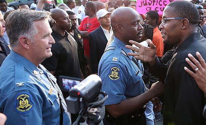 In this Aug. 16, 2014 file photo, Col. Ron Replogle, left, head of the Missouri State Highway Patrol, with Capt. Ron Johnson, talks with Malik Shabazz, right, president of Black Lawyers for Justice and former chairman of the New Black Panther Party, during a march with protesters in Ferguson, Mo. Missouri Gov. Jay Nixon said Wednesday, Feb. 11, 2015 that Replogle plans to retire May 1 after serving five years as superintendent and 31 years with the patrol. 