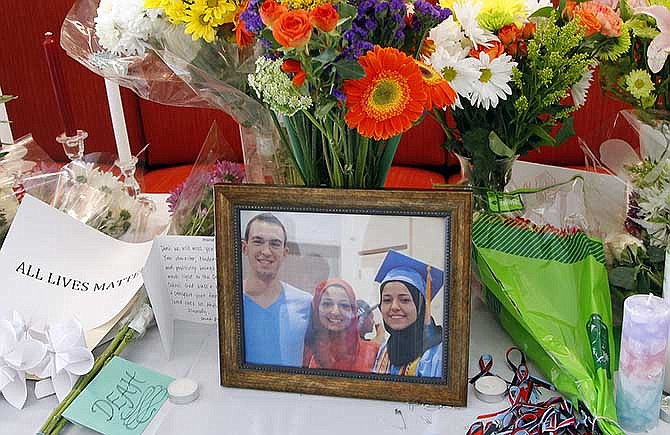 A makeshift memorial appears on display, Wednesday, Feb. 11, 2015, at the University of North Carolina School of Dentistry in Chapel Hill, N.C., in remembrance of Deah Shaddy Barakat, 23, Yusor Mohammad, 21, and Razan Mohammad Abu-Salha, 19, who were killed on Tuesday. Craig Stephen Hicks, 46, has been charged with three counts of first-degree murder in the case. (AP Photo/The News & Observer, Chris Seward) 