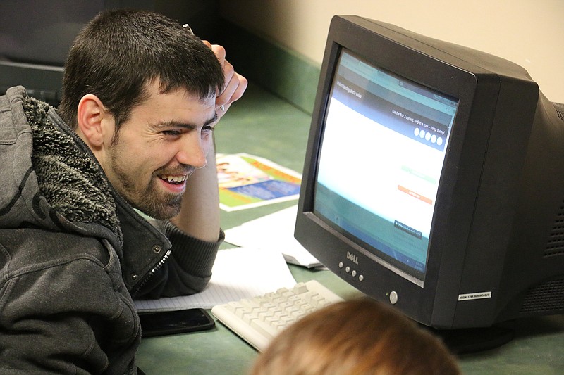 A student laughs with a classmate as he works on High School Equivalency Test (HiSET) material during class Tuesday night.