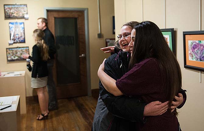 Thompson Center development coordinator Miriam Cullimore, right, gives a hug to Centralia resident Sara Liebig, 14, during a Art for Autism reception and auction at PS Gallery on Feb. 6, 2015 in Columbia, Mo. Thirty-five pieces of art created by Thompson Center patients and family members in the Art for Autism program were on display and for sale. Art for Autism is a free three-week program for patients of the Thompson Center. (AP Photo/The Columbia Daily Tribune, Daniel Brenner)