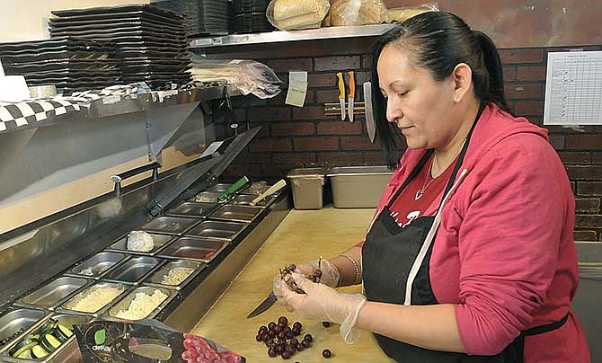 Pam Moreno cuts grapes as she fills containers with ingredients to make dishes at Cafe Via Roma. Moreno has worked at the downtown Jefferson City cafe since before it was purchased by Central Missouri Community Action as a way for employees to gain on-the-job training.