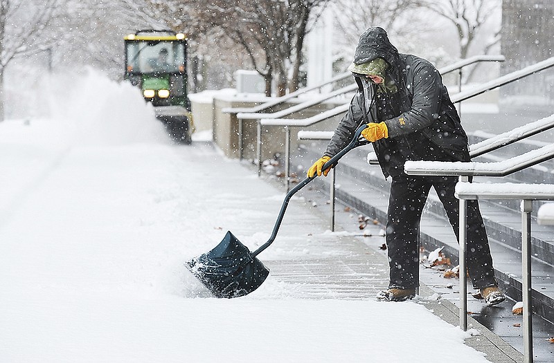 Keith Ziegelbein shovels the snow from between stair railings while John Johnson operates the John Deere motorized brush to clean the sidewalk. The maintenance crew from Central Bank was busy Monday as they cleaned snow from sidewalks and drives around and through the banking facilities. Even though banks were closed today, they spent the day getting ready for Tuesday's regular work day.