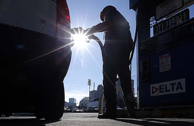 In this Jan. 23, 2015 file photo, Sonu Singh pumps gas for a motorist at a Delta gas station in downtown Newark, N.J., where the cash price for regular unleaded was listed at $1.71. The lowest gas prices in five years had given people more spending money, and hiring was surging. And yet - to the surprise of analysts - consumers have held their wallets closely. 