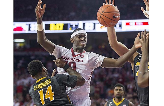 Arkansas forward Bobby Portis, center, passes the ball as Missouri guard Keith Shamburger, left, defends during the first half of an NCAA college basketball game on Wednesday, Feb. 18, 2015, in Fayetteville, Ark. 