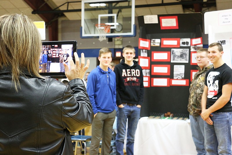 South Callaway High School Principal Heather Helsel takes a photos of a group of students with their project at a history exhibit in the middle school gym Thursday. These students chose to do their project on rebellion groups during the Holocaust. Student Landon Horstman said they chose that subject because they wanted to showcase examples of groups who fought back during that time.