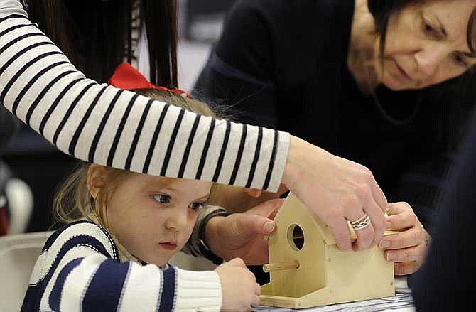 Samantha Boldrey, center, watches closely as her grandmother Sandra Laurich, right, and mother Michelle Boldrey check to make sure the roof is nailed securely to her bird house frame while visiting the Lowe's Kids Construction Zone during the 15th annual Jefferson City Home Builders Association Home Show at Firley YMCA.

