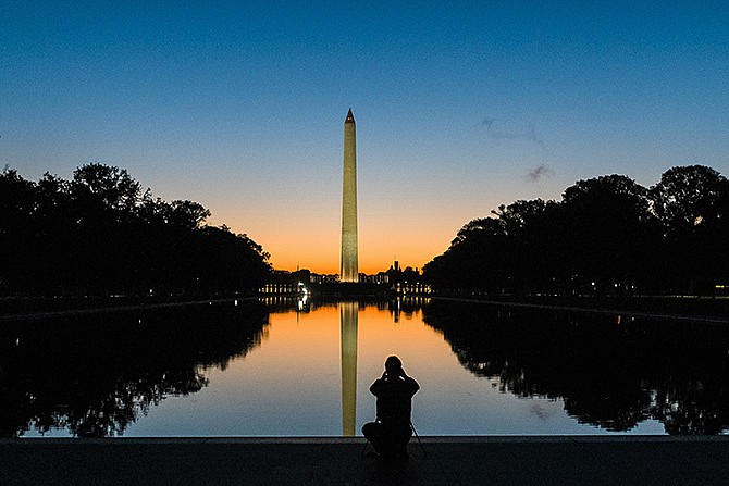 A photographer is silhouetted in the reflecting pool as he captures the sunrise in October behind the Washington Monument. Government surveyors have determined a new height for the Washington Monument that's nearly 10 inches shorter than what has been thought for more than 130 years.