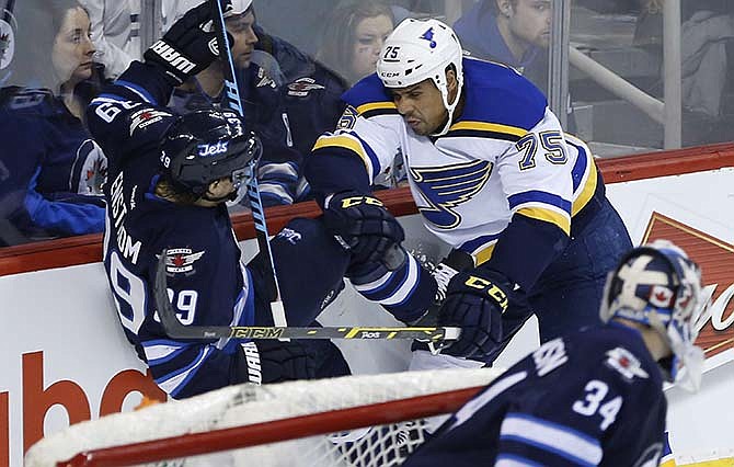 Winnipeg Jets' Toby Enstrom (39) gets checked by St. Louis Blues' Ryan Reaves (75) as Jets goaltender Michael Hutchinson (34) watches during the second period of an NHL hockey game Thursday, Feb. 26, 2015, in Winnipeg, Manitoba. 
