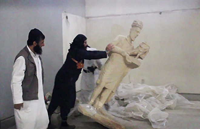 In this image made from video posted on a social media account affiliated with the Islamic State group shows a militant toppling an ancient artifact on Thursday in the Ninevah Museum in Mosul, Iraq. The extremist group has destroyed a number of shrines - including Muslim holy sites - in order to eliminate what it views as heresy.