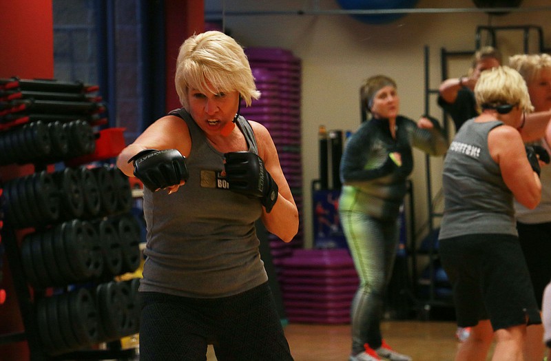A YMCA Body Combat class instructor shows class participants what moves to make during their workout Wednesday night.