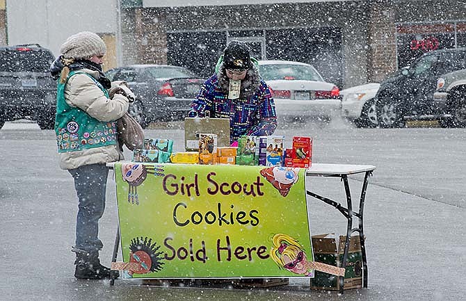 Audrey Cook, 11, waits as Eleanor Bax, 13, searches for change for the $20 bill in her teeth Saturday as they sell Girl Scout Cookies in the Mart Shopping Center parking lot in Jefferson City. Girls from troops 62018 and 30488 of St. Martins stood in the snow from 11 a.m.-3 p.m. in an attempt to sell all the cookies they had with them. By the time the girls had finished their Saturday sales, Mid-Missouri was caught in the brunt of a new winter storm. By 9 p.m., approximately 2Â½ inches of snow had fallen, and total accumulations of up to 5 inches were expected in Jefferson City area by the time the snow tapers off later today.