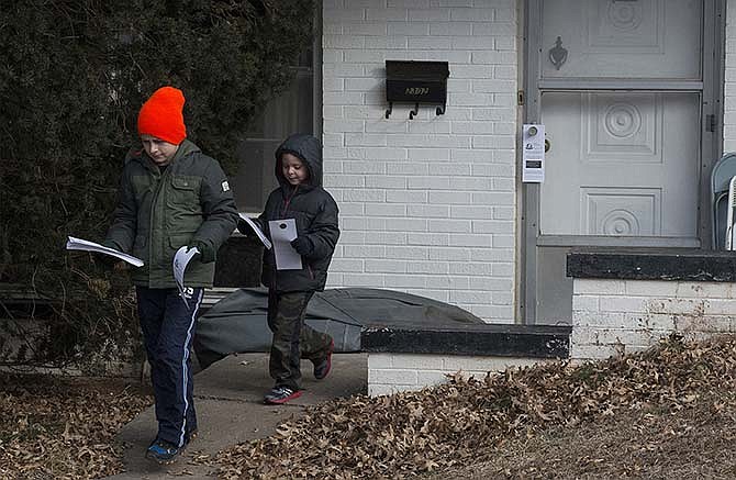 
From left, scouts Evan Gerber, 9, and Brett Brooks, 7, go door to door leaving tags on doors Saturday. Boy Scouts and Cub Scouts in Jefferson City walked the streets Saturday morning as they hung tags on people's doors in hopes of gathering non-perishable food items for their Scouting for Food drive next Saturday.