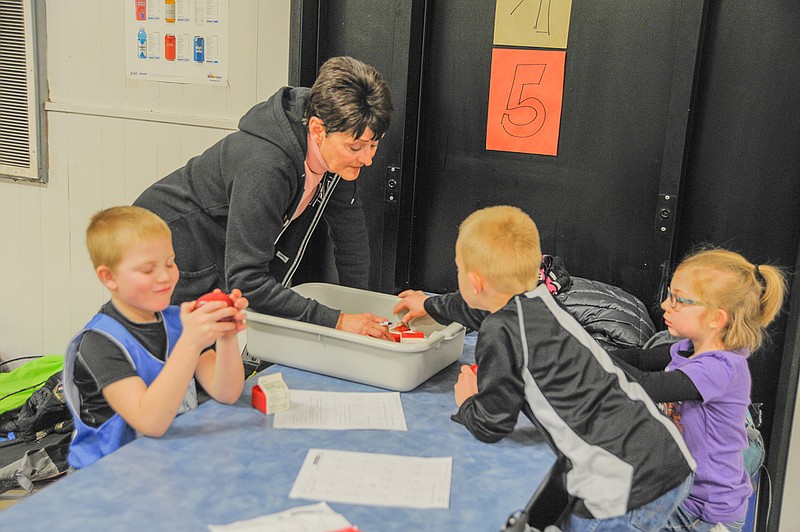 Landen Hentges studies his after-school snack while Justin Seaver and Ella Stanley choose a milk at the Russellville Elementary School's new after school care program with Gail Cartee.