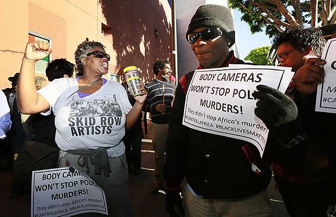 Suzette Shaw, left, a homeless woman, joins others protesting a police shooting of a homeless man on Tuesday, March 3, 2015, in downtown Los Angeles. There was a moment of silence at the site of the shooting where several dozen people rallied Tuesday in protest. The group then marched toward the downtown police administration building, the site of a meeting of the city Police Commission, a panel of civilians who oversee the Police Department.