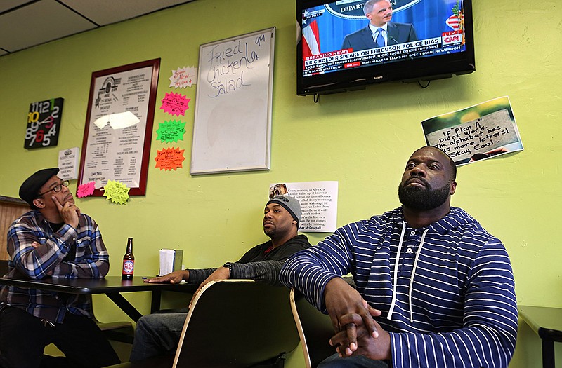 David Johnson, left, Mark Taylor and Charles Strozier watch as U.S. Attorney General Eric Holder makes a televised announcement, Wednesday in Ferguson.
