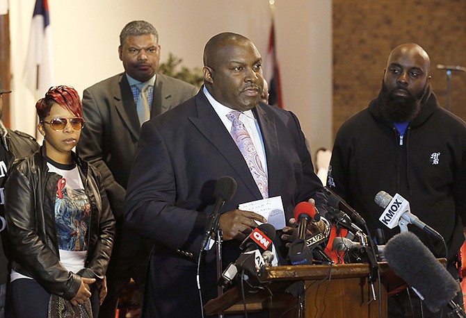 Attorney Daryl Parks, center, talks to reporters as Lesley McSpadden, left, and Michael Brown Sr., right, parents of 18-year-old Michael Brown Jr., listen during a news conference on Thursday in Dellwood.