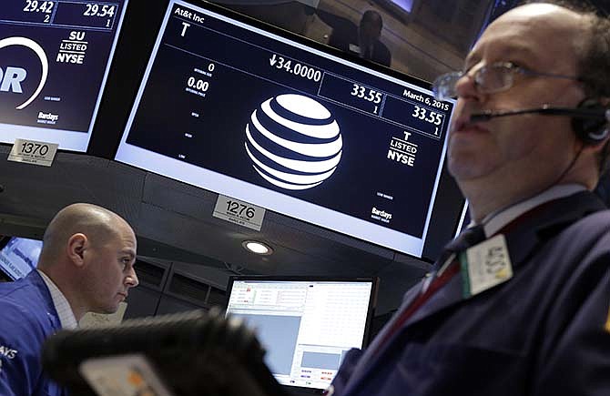 A trader, right, works at the post that handles AT&T on the floor of the New York Stock Exchange, Friday, March 6, 2015. Apple will replace AT&T in the Dow Jones industrial average, the managers of the index announced early Friday.