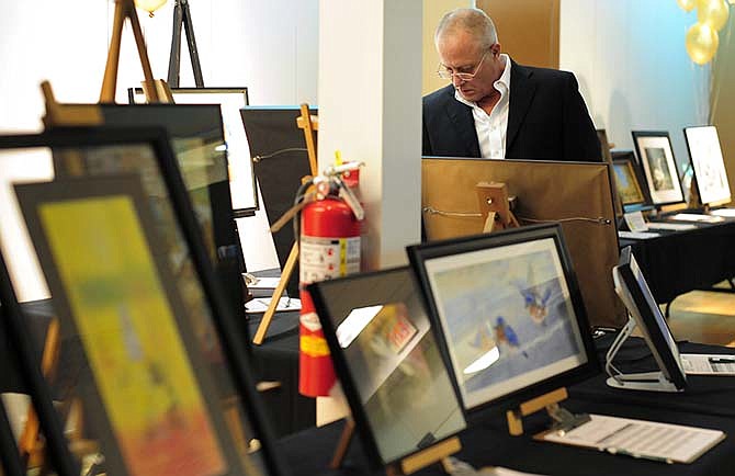 Joe Neuenswander, father of HALO founder Rebecca Neuenswander Welsh, looks at some of the pieces of art up
for auction Friday, March 6, 2015 during the 7th annual HALO ArtReach Auction and 10th birthday celebration at Capital Mall in Jefferson City.