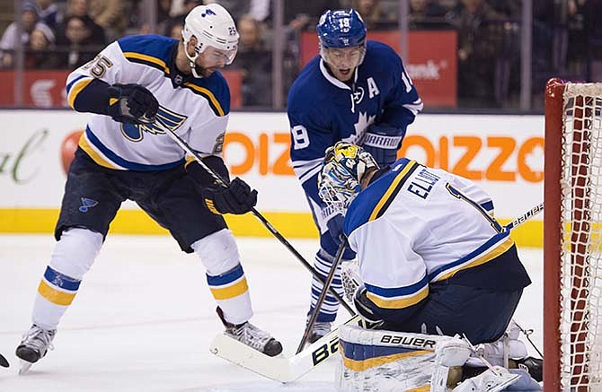 St. Louis Blues goaltender Brian Elliott makes a save as defenseman Chris Butler (25) holds off Toronto Maple Leafs left winger Joffrey Lupul during the second period of an NHL hockey game Saturday, March 7, 2015, in Toronto.