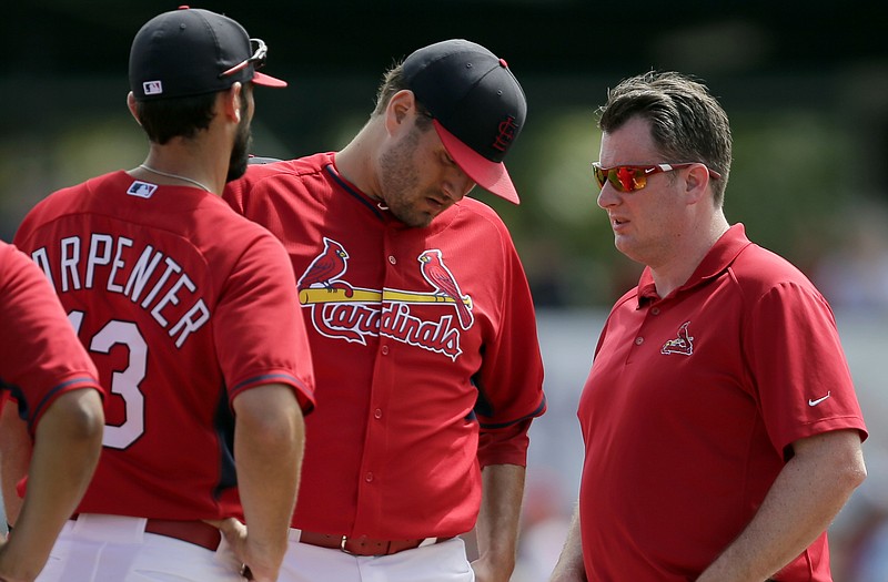 Cardinals starting pitcher Lance Lynn (center) talks with trainer Chris Conroy as Matt Carpenter looks on during Sunday's game against the Marlins in Jupiter, Fla.