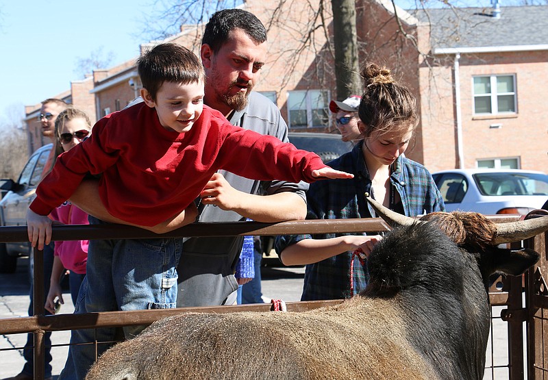 A young boy leans over the fence to pet animals at the petting zoo in the Mueller Student Center parking lot at Westminster College Saturday. Two student groups on campus brought the petting zoo to campus for the afternoon.