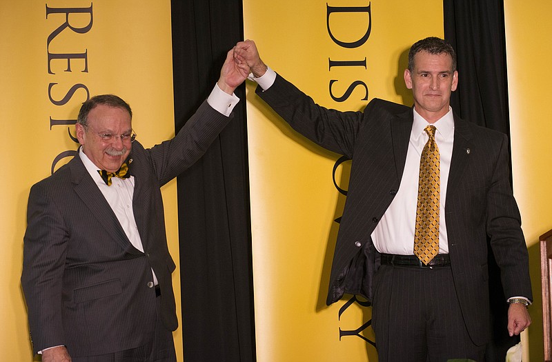 University of Missouri chancellor R. Bowin Loftin (left) raises the hand of new athletic director Mack Rhoades during a news conference Tuesday in Columbia.