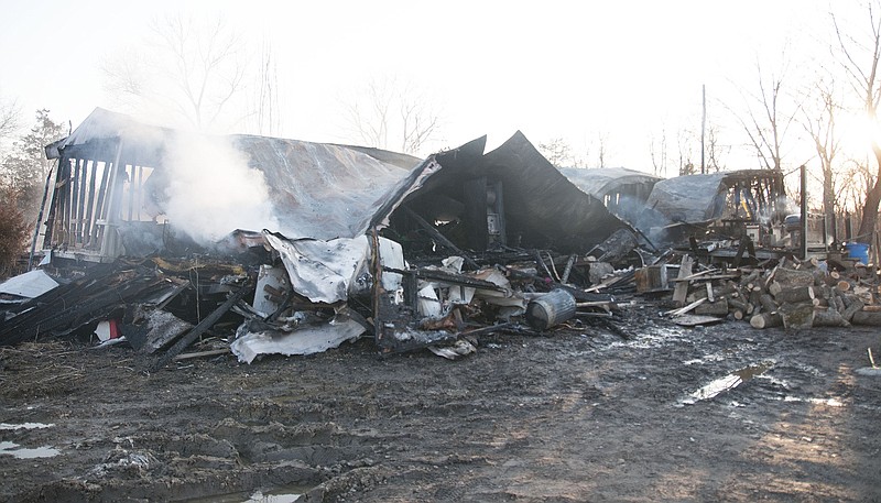 The home at 5521 State Route D in Williamsburg smolders after a late morning fire on Wednesday. Jason and Tonya Ballard and their 16-year-old daughter lived in the home and were not home during the fire. The family, though, lost their two dogs and eight birds.