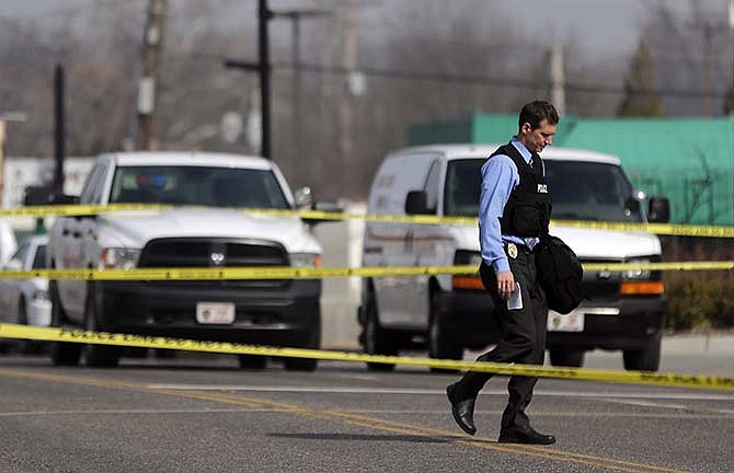 A police officer walks toward the Ferguson Police Department Thursday, March 12, 2015, in Ferguson, Mo. Two officers were shot in front of the police department early Thursday as demonstrators gathered after the police chief resigned in the wake of a scathing Justice Department report alleging bias in the police force and local courts.