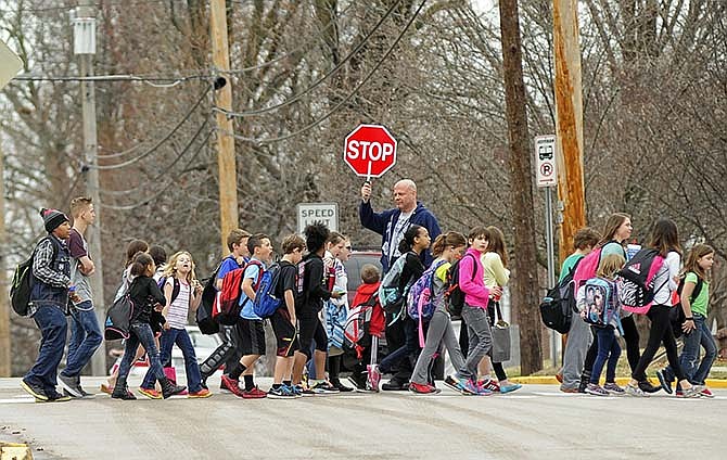 Student teacher Ed Neeley holds traffic at bay while serving as a crossing guard for West Elementary students as they pour across West Main Street and into the weekend following the final bell on Friday afternoon in Jefferson City.