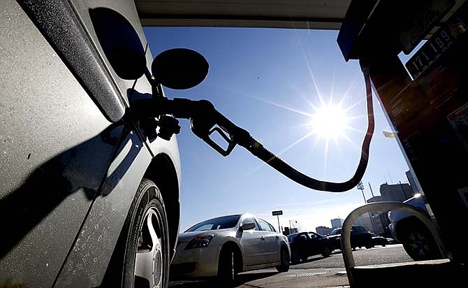 In this Jan. 23, 2015, file photo, vehicles form a line behind a motorist re-fueling at a gas station, in Newark, N.J. Oil has fallen close to its lowest level in 6 years, and many expect it to fall much further in the coming weeks because supplies are still heading up and the summer driving season is still months away. 