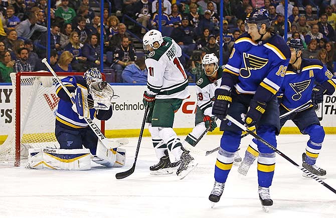St. Louis Blues goalie Brian Elliott makes a glove save as Minnesota Wild's Zach Parise looks for the rebound during the second period of an NHL hockey game Saturday, March 14, 2015, in St. Louis.