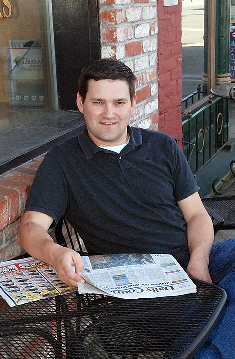 Travis Morgan sits with a newspaper outside a coffee shop in Grants Pass, Ore. The 33-year-old pilot still likes reading a printed newspaper, watching the news on his television, and using a search engine to dig more deeply if he wants to know more. 