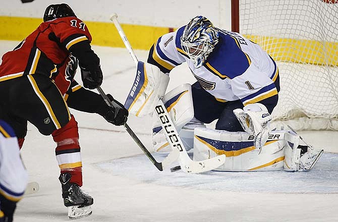 St. Louis Blues goalie Brian Elliott, right, blocks a shot from Calgary Flames' Mikael Backlund, from Sweden, during the second period of an NHL hockey game, Tuesday, March 17, 2015 in Calgary, Alberta.