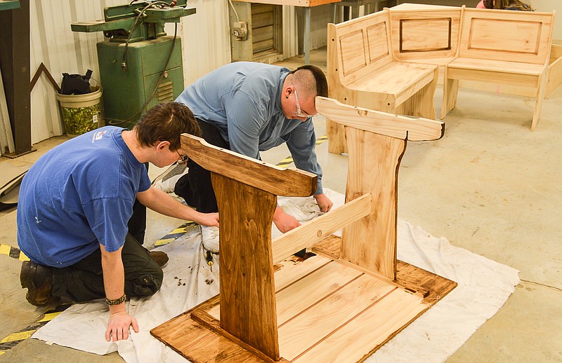 Russellville High School woods class students Willie Catanzaro and Chris Wolfe restore restaurant booths, which will be installed in the school cafeteria as it transitions into the War Tribe Cafe.