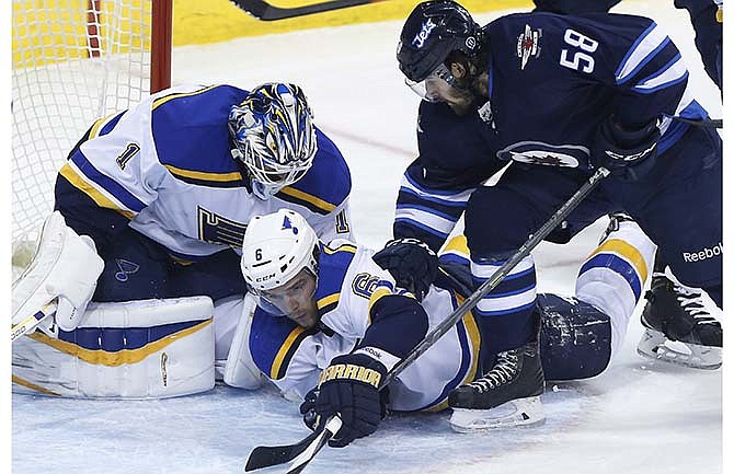 St. Louis Blues goaltender Brian Elliot jumps on the puck as Blues' Zbynek Michalek (6) is pushed to the ice by Winnipeg Jets Eric O'Dell (58) during the first period of an NHL hockey game Thursday, March 19, 2015, in Winnipeg, Manitoba. 