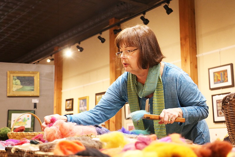Gail Barnickol of Jefferson City picks out wool to blend together using a wood and metal comb. Barnickol taught a class about wool felting on Wednesday at Art House. "Most of the fun is putting the colors together," she told the class Wednesday.
