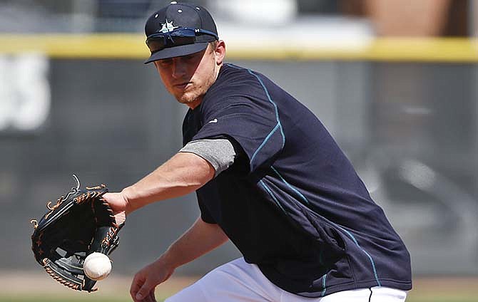 Seattle Mariners third baseman Kyle Seager fields a hard hit ball while taking infield practice before a spring training baseball game against the Kansas City Royals, Thursday, March 26, 2015, in Peoria, Ariz.