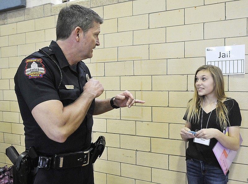 Officer Kevin Kempker puts Anna Hirsch in jail for failure to pick up her children from day care. Hirsch was assigned a scenario in which she ended up in jail as part of an exercise designed to show young people what can happen to them if they fail to pay their rent or mortgage.