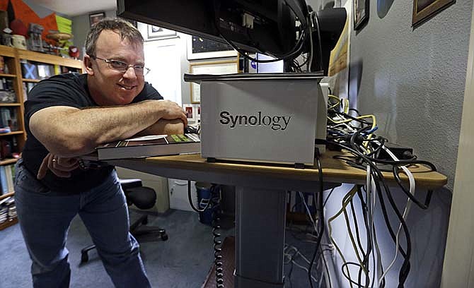 Mike Loucks poses in his home space exploration engineering office, with a tangle of dedicated cables behind, Thursday, March 26, 2015, in Friday Harbor, Wash., in the San Juan Islands. Loucks lost Internet and phone service during a 10-day outage on the island in 2013. Other regions around the country also have fallen dark in recent years, sometimes for days at a time, because of failures or accidents affecting the nation's broadband infrastructure. The failures have revealed vulnerabilities in the backbone of the nation's high-speed Internet highway, which often lacks the detour routes necessary to quickly restore service when outages occur outside of major cities.