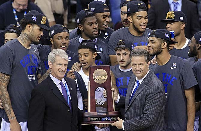 Kentucky coach John Calipari, right, holds the regional championship trophy after the team's 68-66 win over Notre Dame in a college basketball game in the NCAA men's tournament regional finals, Saturday, March 28, 2015, in Cleveland. Kentucky advanced to the Final Four at 38-0. 