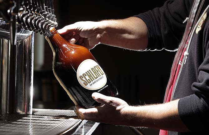 In this photo made Friday, March 27, 2015, an employee demonstrates for a photograph the pouring of a growler of beer at Schlafly Tap Room in St. Louis. A bill is moving through the Missouri Legislature that would allow the sale of jugs of beer, known as growlers, at convenience and grocery stores. Currently the jugs, which are usually filled with craft brews so beer lovers can drink the fresh beverages at home, are only found at breweries and some bars. 