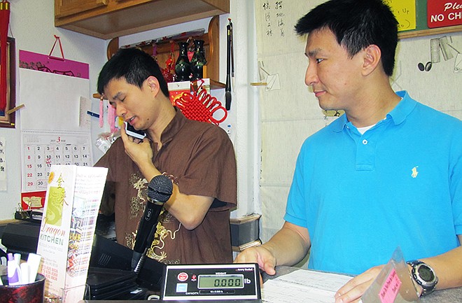 Danny Cheng, right, is behind the counter to wait on a customer as cashier Fei Lin answers questions over the phone. Cheng's restaurant, Dragon Kitchen, was awarded the first Salvation Army Countertop Red Kettle Award for raising money for the Salvation Army.

