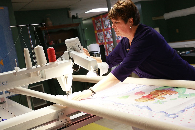 Cherlyn Grubbs uses a longarm machine to make a quilt at Rooster Creek in Holts Summit. The quilting and sewing business opened its doors in June and has developed a community of regulars since then.